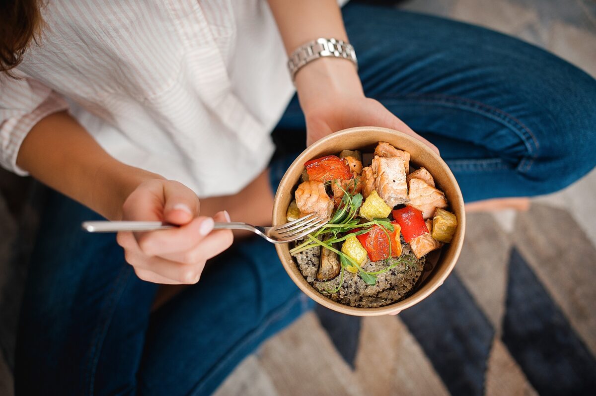 Girl,holds,a,paper,plate,with,healthy,food,sitting,on