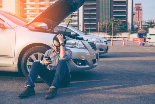 Young,asian,handsome,man,sitting,by,the,broken,down,car