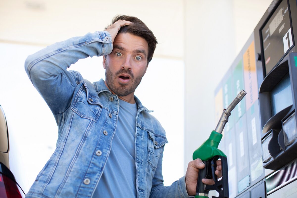 Emotional,businessman,counting,money,with,gasoline,refueling,car