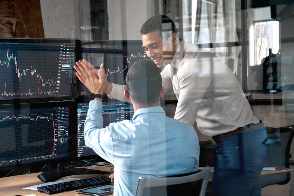 Two,men,colleagues,traders,sitting,at,desk,at,office,monitoring