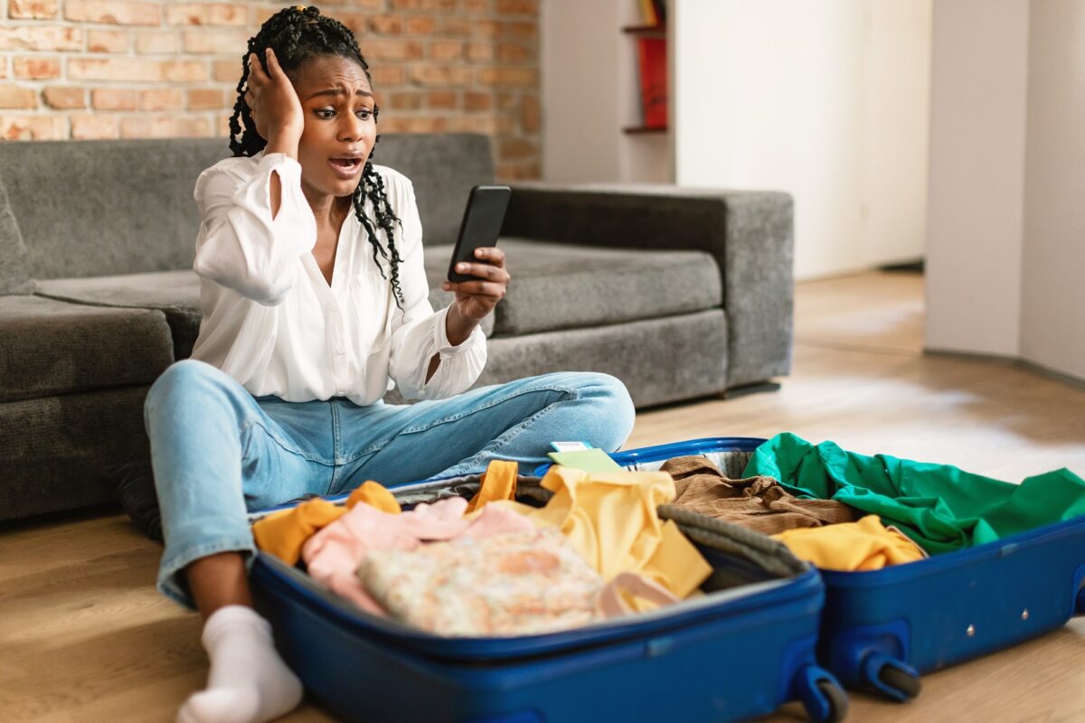 Traveling,problems,concept.,shocked,black,woman,using,cellphone,and,reading