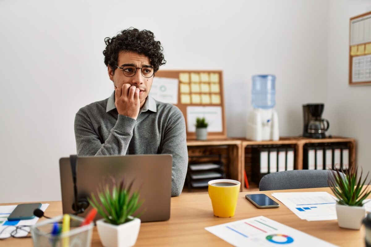 Young,hispanic,man,wearing,business,style,sitting,on,desk,at