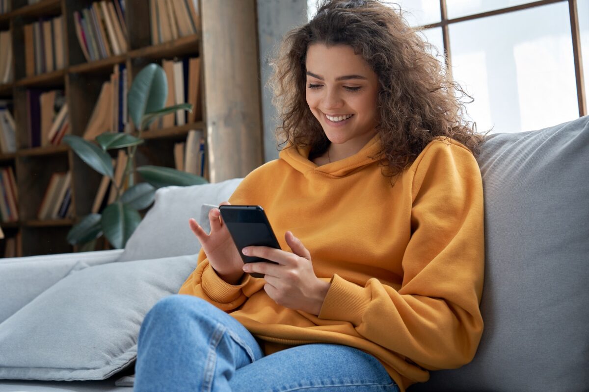 Happy,millennial,hispanic,teen,girl,checking,social,media,holding,smartphone