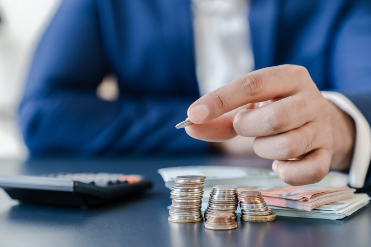 Businessman,holding,euro,cents,coins,dollar,bills,on,table,with