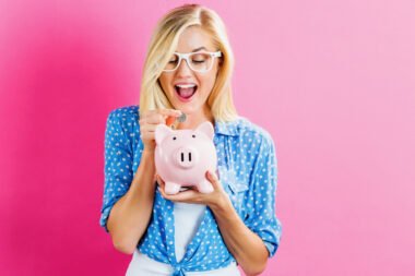 Young,woman,with,a,piggy,bank,on,a,pink,background