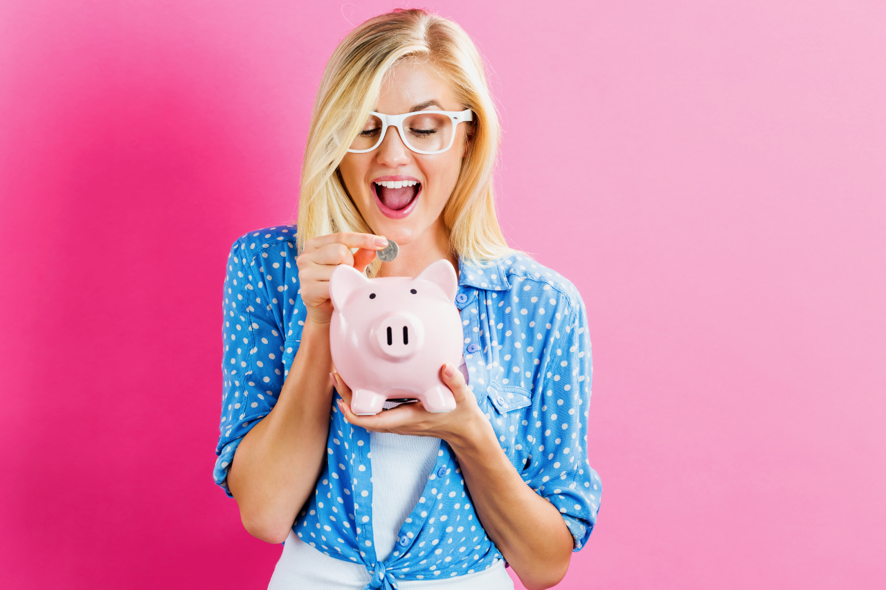 Young,woman,with,a,piggy,bank,on,a,pink,background