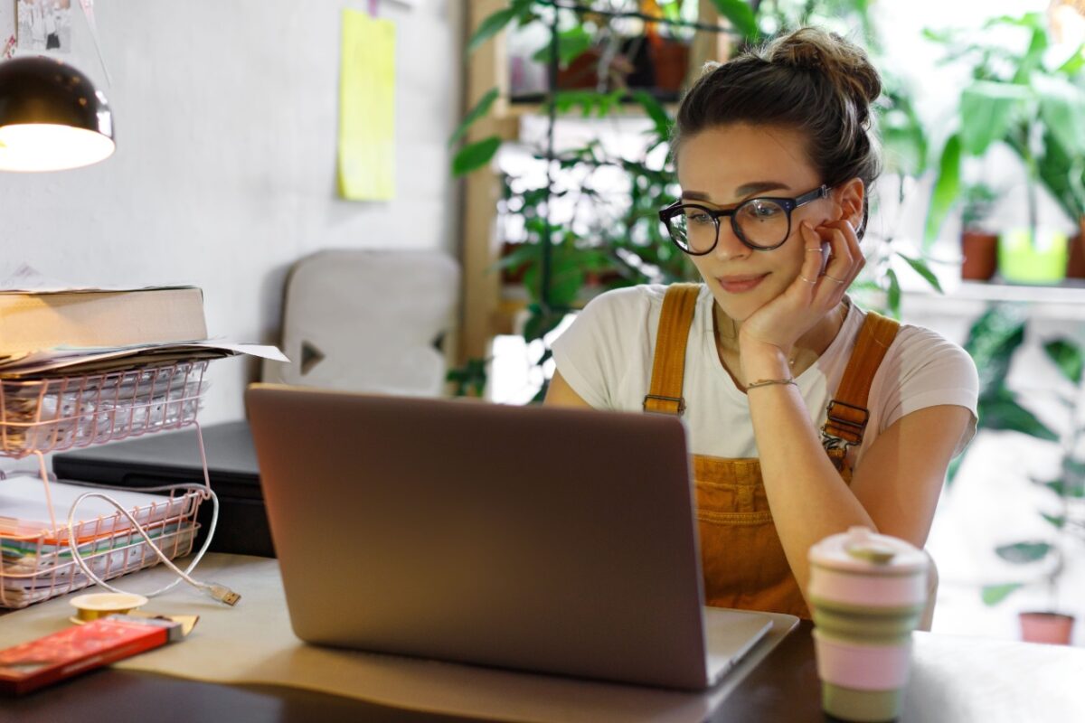 Young,female,gardener,in,glasses,using,laptop,,communicates,on,internet