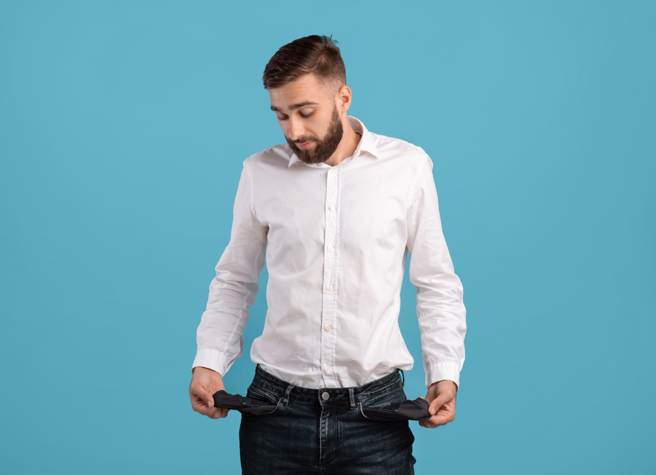 Young,bearded,man,showing,empty,pockets,on,blue,studio,background.