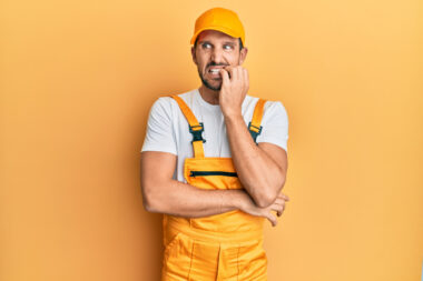 Young,handsome,man,wearing,handyman,uniform,over,yellow,background,looking