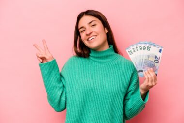 Young,caucasian,woman,holding,banknotes,isolated,on,pink,background,joyful