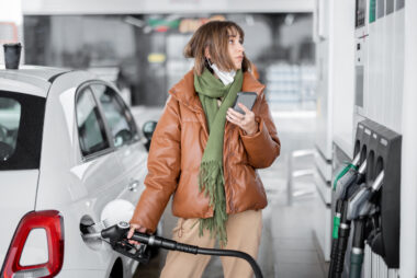 Woman,refueling,car,with,gasoline,,using,smartphone,to,pay.,concept