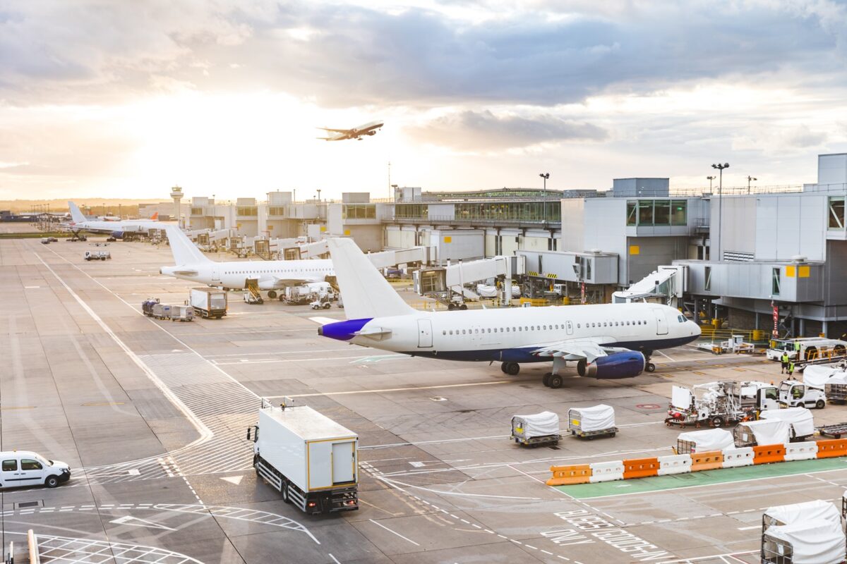 Busy,airport,view,with,airplanes,and,service,vehicles,at,sunset.