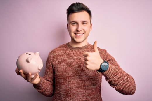 Young,handsome,caucasian,man,holding,piggy,bank,for,savings,over