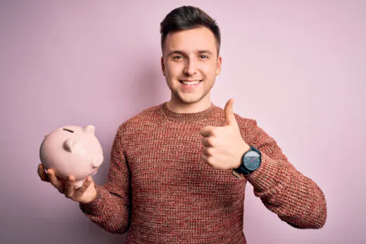 Young,handsome,caucasian,man,holding,piggy,bank,for,savings,over