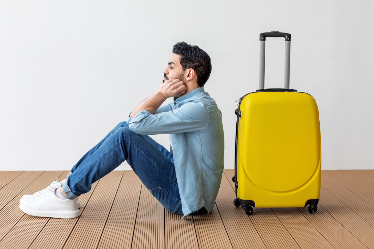Upset,arab,male,tourist,sitting,near,suitcase,and,looking,away