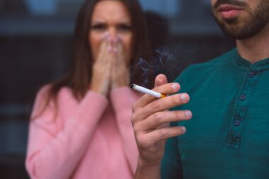 Passive,smoking.,man,smoking,cigarette,near,woman,covering,her,face