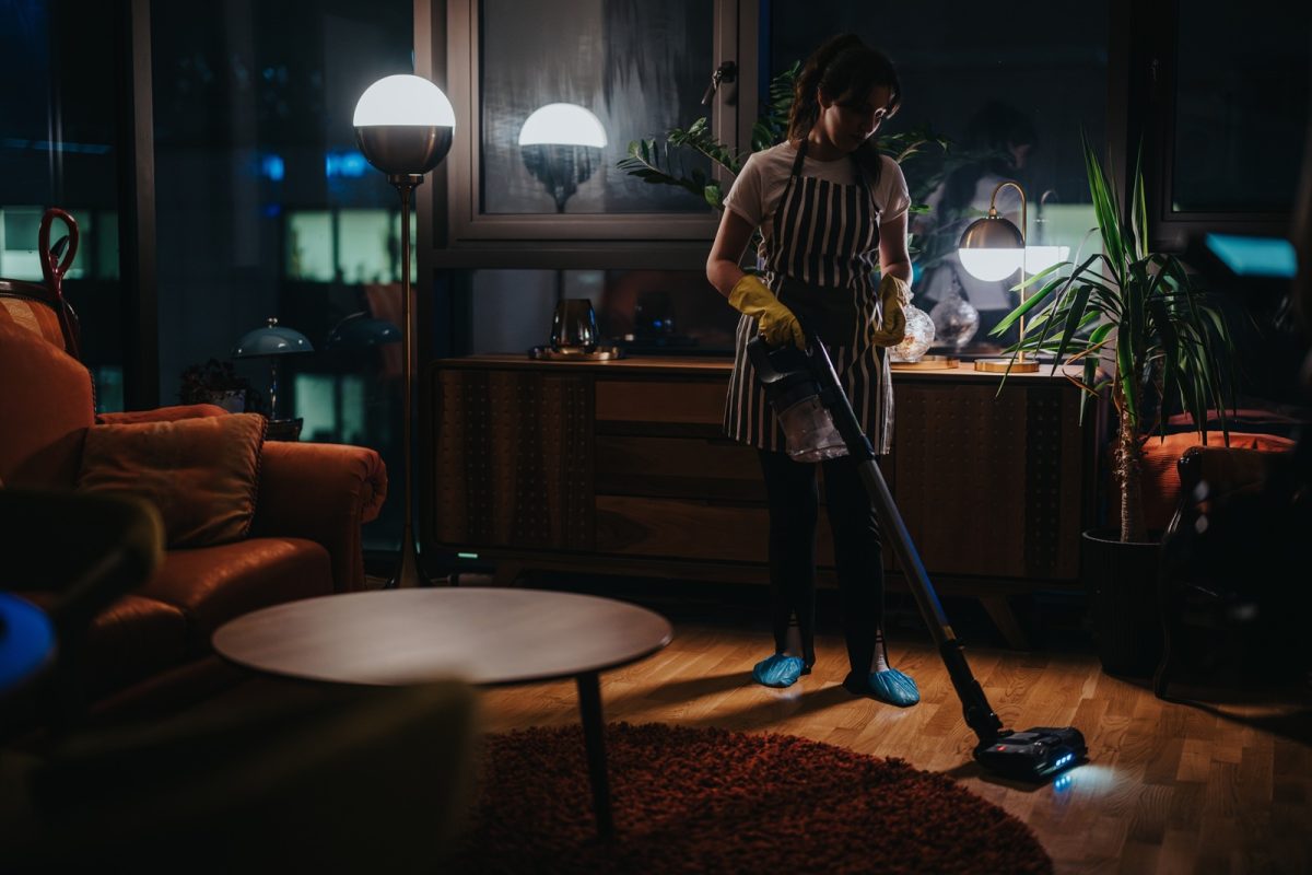 A,woman,is,vacuuming,the,wooden,floor,of,a,stylish