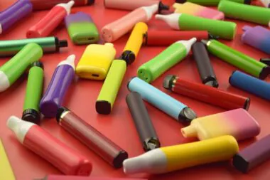 Set,of,multicolor,disposable,electronic,cigarettes,on,a,red,background.