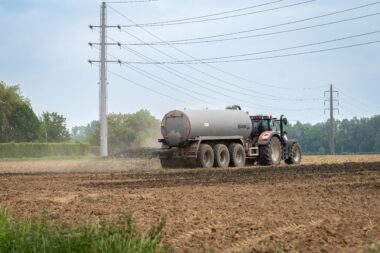 A tractor fertilizing a rural field with liquid manure for agriculture.