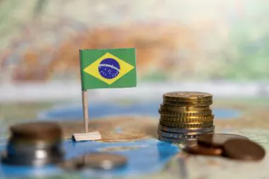 Brazilian,flag,with,stacks,of,coins,on,a,map,,symbolizing