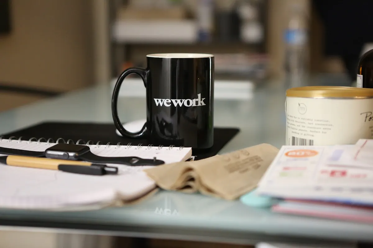 Bureau de travail avec tasse WeWork, fournitures de bureau et documents.