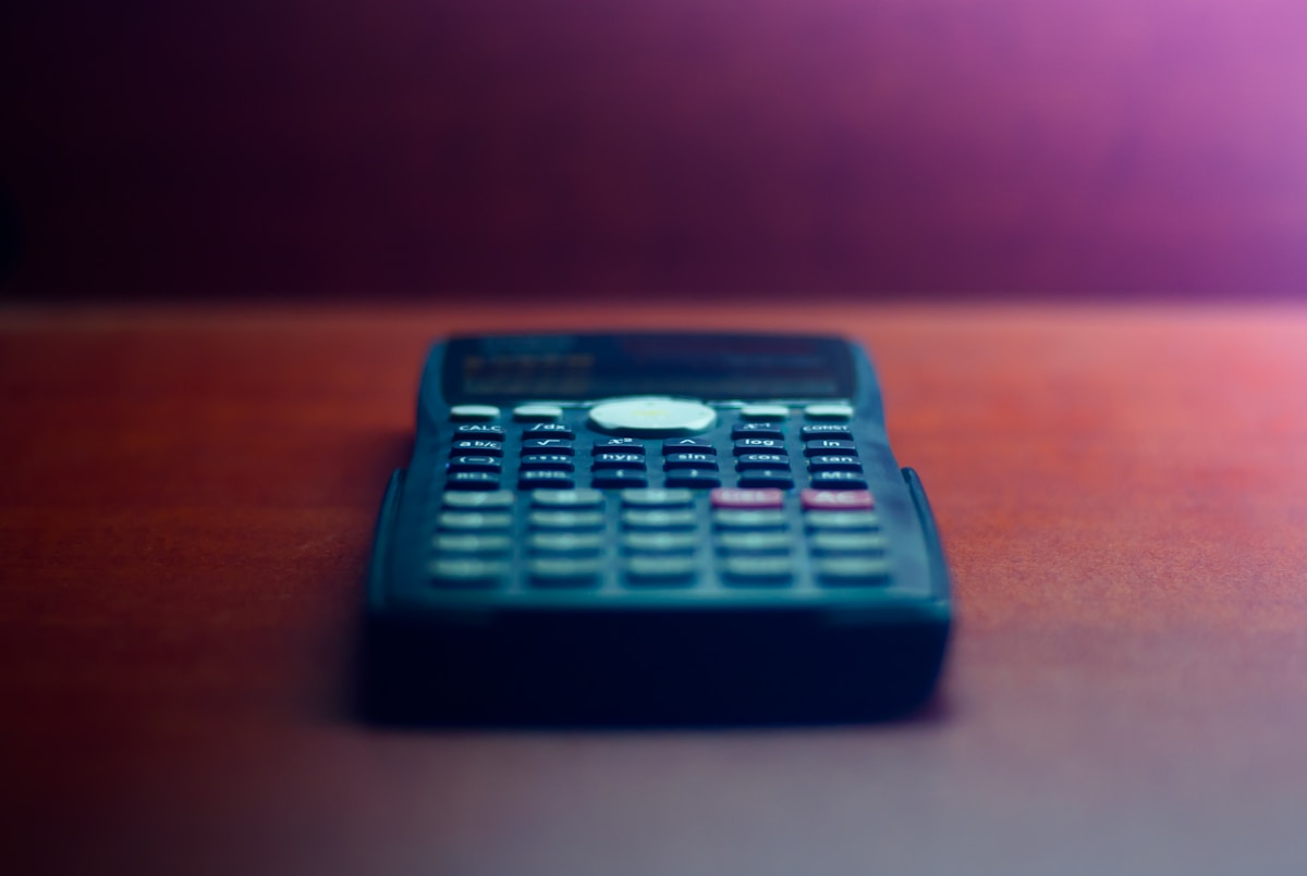 Calculatrice de bureau bleue sur fond sombre et coloré.