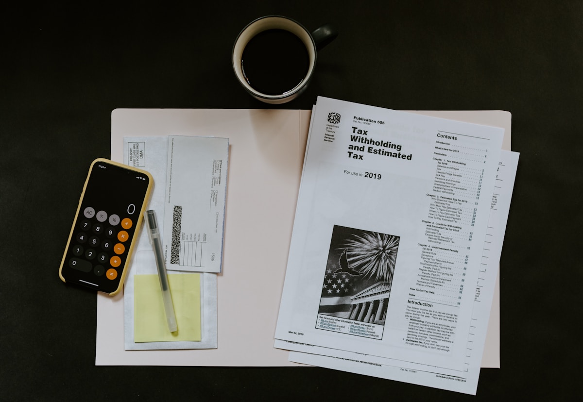 Bureau de travail avec documents fiscaux, calculatrice et tasse de café.