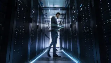 Male,it,engineer,walking,and,working,in,data,center,corridor.