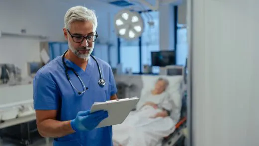 Hospital,doctor,reviews,a,old,patient's,medical,report,,delivering,bed