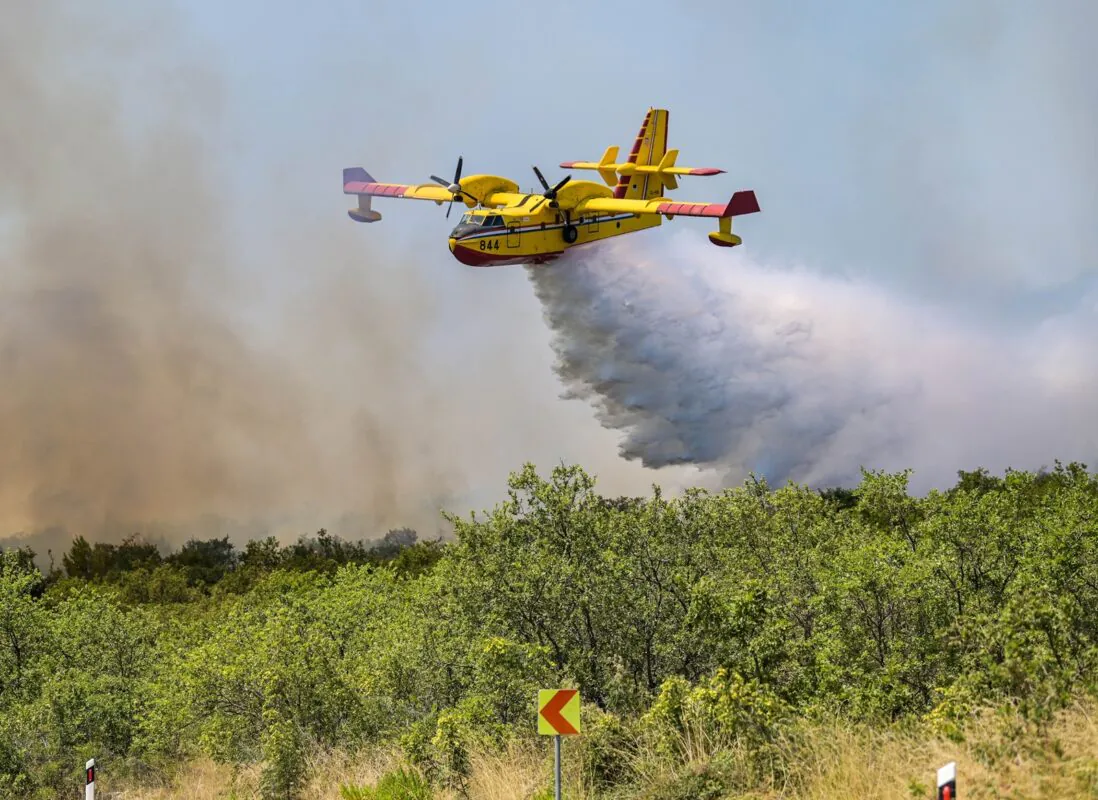 An,aerial,firefighting,plane,releasing,water,over,a,forest,fire,