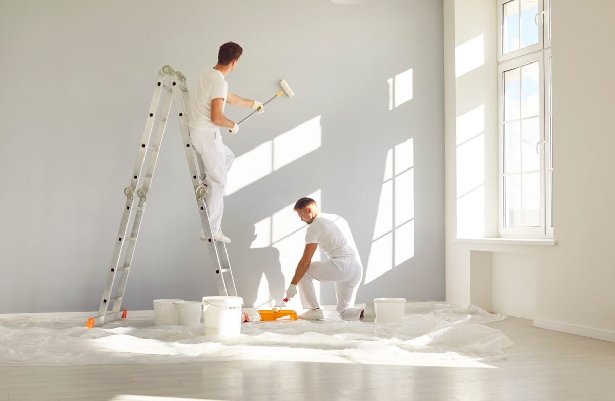 Team,of,professional,painters,in,white,clothes,painting,a,grey