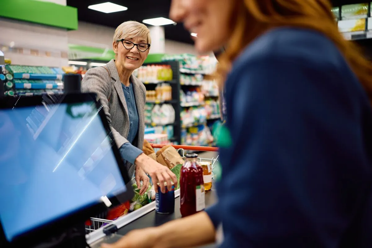 Happy,senior,woman,paying,for,groceries,at,cash,register,in
